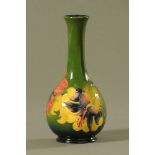 A Moorcroft tube lined pottery "Hibiscus" pattern bottle shaped vase, decorated on a green ground,