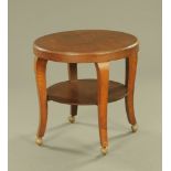 A 1920's oak two tier circular occasional table, on later Shepherd castors.