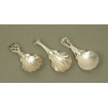 Three George III silver caddy spoons of similar design, with pierced terminals and scalloped bowls,