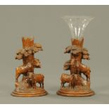 A pair of Black Forest carved wooden stands, cattle and tree trunks.
