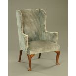 An 18th century oak wing back armchair, with shaped wings and scrolled outswept arms,