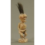 An African carved and painted wood figure of a seated man holding a bowl and with Mohican style