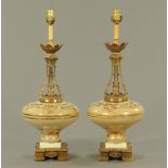 A pair of brass and glass table lamps, with square bases each raised on four short feet.