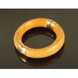 An antique ivory bangle, with yellow coloured metal mounts.