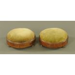 A pair of Victorian walnut circular footstools, the tops upholstered in green cloth, on turned feet.