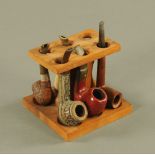 A Fairfax teak six division pipe rack, containing 5 pipes including a Stanwell 42 Royal Rouge pipe.