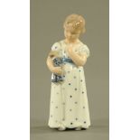 A Royal Copenhagen porcelain figure of a standing girl holding a doll, 14.5 cm high, No.