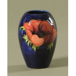 A Moorcroft tube lined pottery "Anemone" pattern vase., decorated on a dark blue ground.