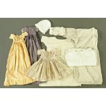 A collection of vintage clothing, including lace bonnet, various pleated dresses, undergarments,