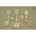 Eight early 19th century filigree white metal caddy spoons, of varying designs,