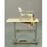 An industrial Singer sewing machine, with table for same, with safety switch and pedal function.