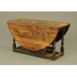 An 18th century oak oval gate leg table, on slender baluster turned supports.