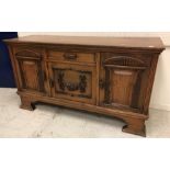 An early 20th Century oak sideboard the plain top above a single drawer by flanked by two cupboards