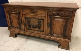 An early 20th Century oak sideboard the plain top above a single drawer by flanked by two cupboards