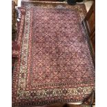 A Persian Bijr rug, with all-over lozenge medallions and stylised floral decoration on a red ground,