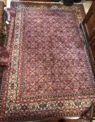 A Persian Bijr rug, with all-over lozenge medallions and stylised floral decoration on a red ground,