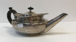 A George IV silver teapot of squashed oval form with applied gadrooned edge and ebonized handle (by