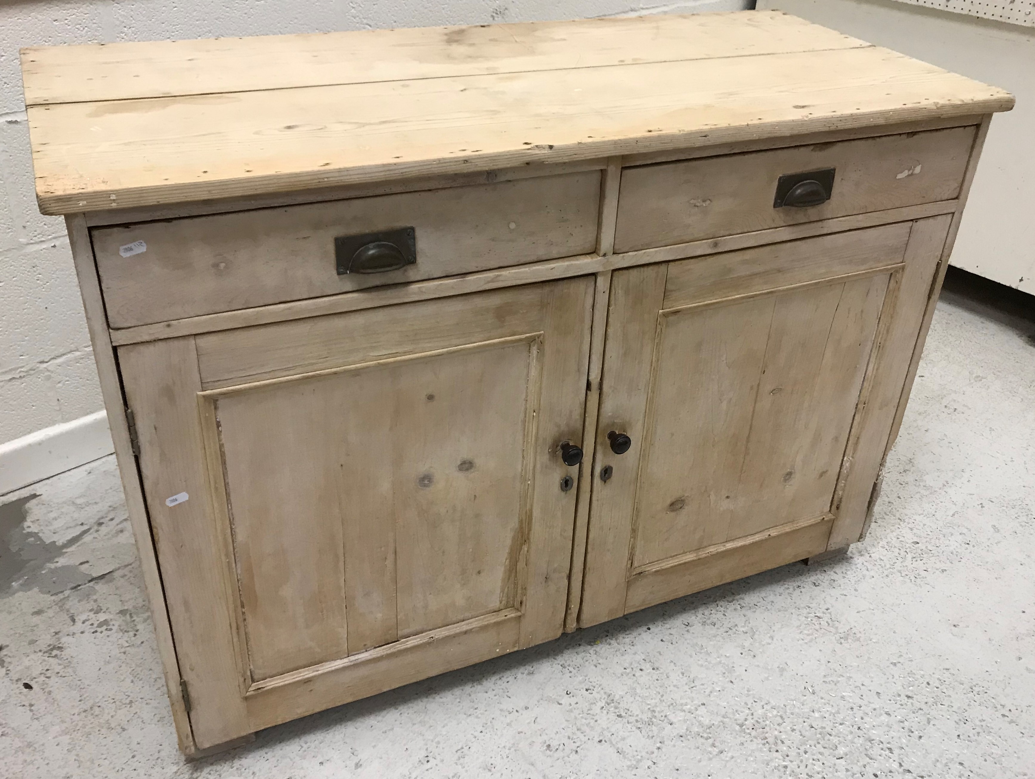 A circa 1900 Polish limed pine larder cupboard with two drawers over two cupboard doors with tin