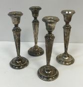 A composite set of four matching George V silver table candlesticks with beaded decoration with