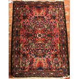 A Sarouk rug, the central panel set with floral motifs on a red ground, within a stepped red,