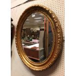 A gilt and gesso oval wall mirror with foliate decoration to the edge, approx 77 cm x 66 cm,