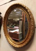 A gilt and gesso oval wall mirror with foliate decoration to the edge, approx 77 cm x 66 cm,