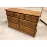 A modern pine chest of three short over a bank of four long drawers on bun feet,