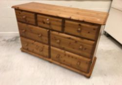 A modern pine chest of three short over a bank of four long drawers on bun feet,