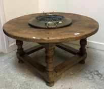 An oak circular occasional with integeral brass twin handled bowl to centre,