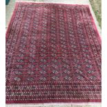 A Tekke Bokhara design rug with all-over elephant foot medallions on a plum ground,