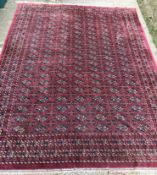 A Tekke Bokhara design rug with all-over elephant foot medallions on a plum ground,