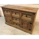 A modern pine dresser with a bank of three central drawers flanked by drawers over cupboard doors,