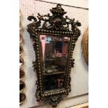 A 20th Century giltwood and gesso wall mirror in the Rococo taste with mask and gryphon decoration,