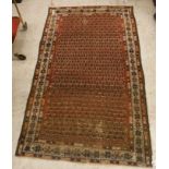 A Malayer rug, the central panel set with all-over stylised hook motifs on a red ground,