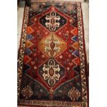 A Bokhara rug, the central panel set with elephant foot style medallions on a red ground,