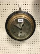 A brass cased ship's wall clock by Barkers of Kensington with silvered dial and arabic numerals