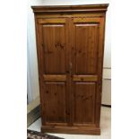 A modern pitch pine two-door wardrobe enclosing a single shelf and hanging space on plinth base,