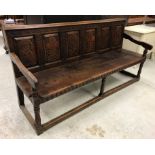 A circa 1900 oak settle, the carved six panel back decorated with flowers in the Aesthetic taste,
