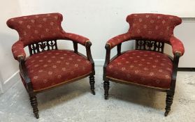 A pair of late Victorian mahogany framed and upholstered low tub chairs with carved swag and urn