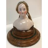 A mid-19th Century German glazed porcelain doll's head and shoulder mount with real hair in plaits,