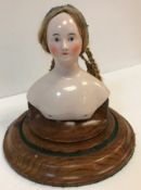 A mid-19th Century German glazed porcelain doll's head and shoulder mount with real hair in plaits,