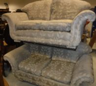A pair of scroll arm two seat sofas in gold floral decorated upholstery,