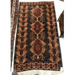 A 20th Century Persian rug with three repeating medallions on a dark brown/burgundy ground within a