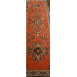 A modern Persian runner with floral medallion decoration on a red ground,