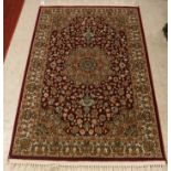A modern Persian Kashan rug with centre medallion on a red ground within a cream ground border,