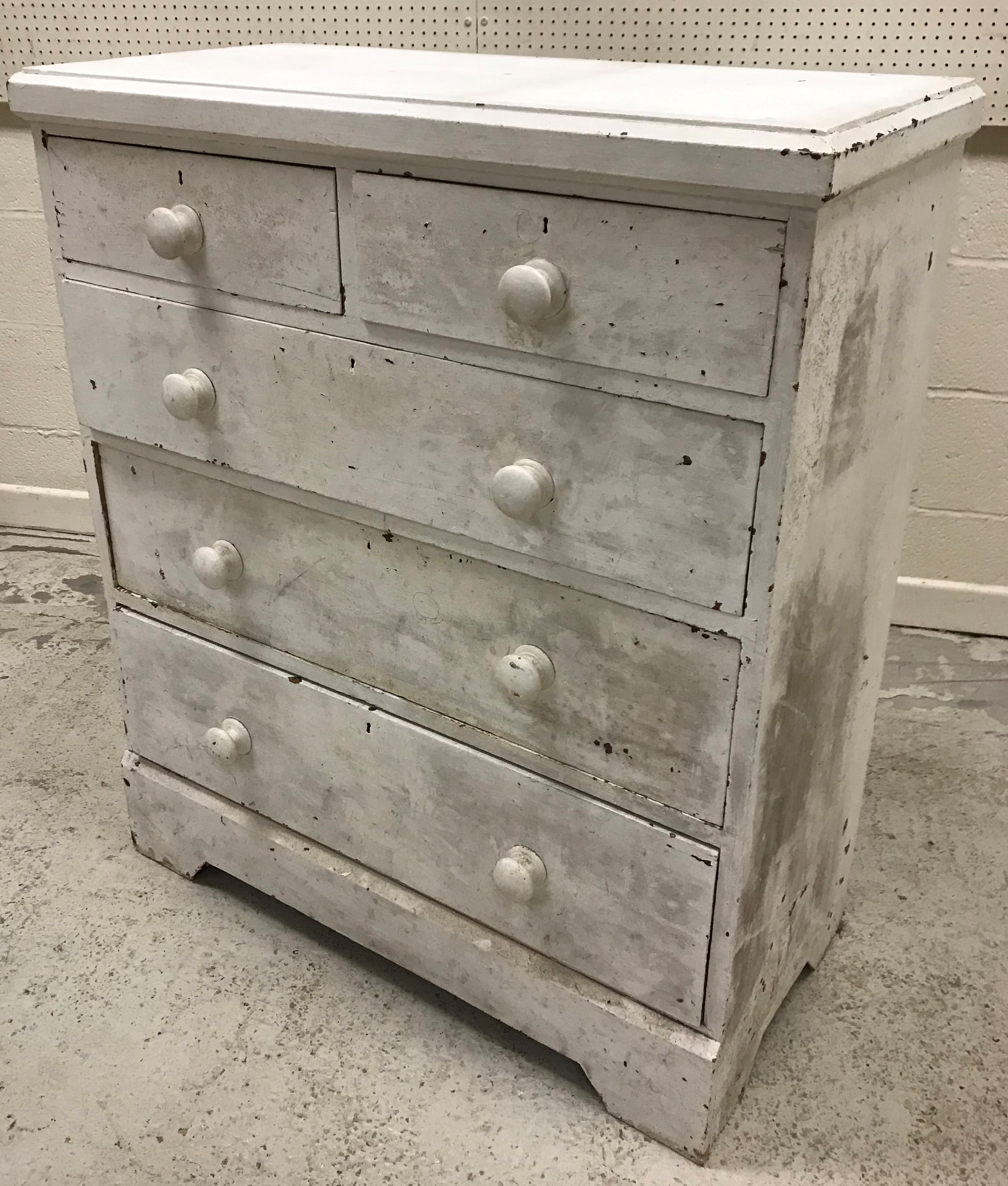 A late Victorian white painted pine chest of two short over three long graduated drawers with