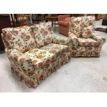 A modern upholstered two seat sofa and matching armchair with cream ground floral decorated loose