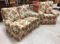 A modern upholstered two seat sofa and matching armchair with cream ground floral decorated loose