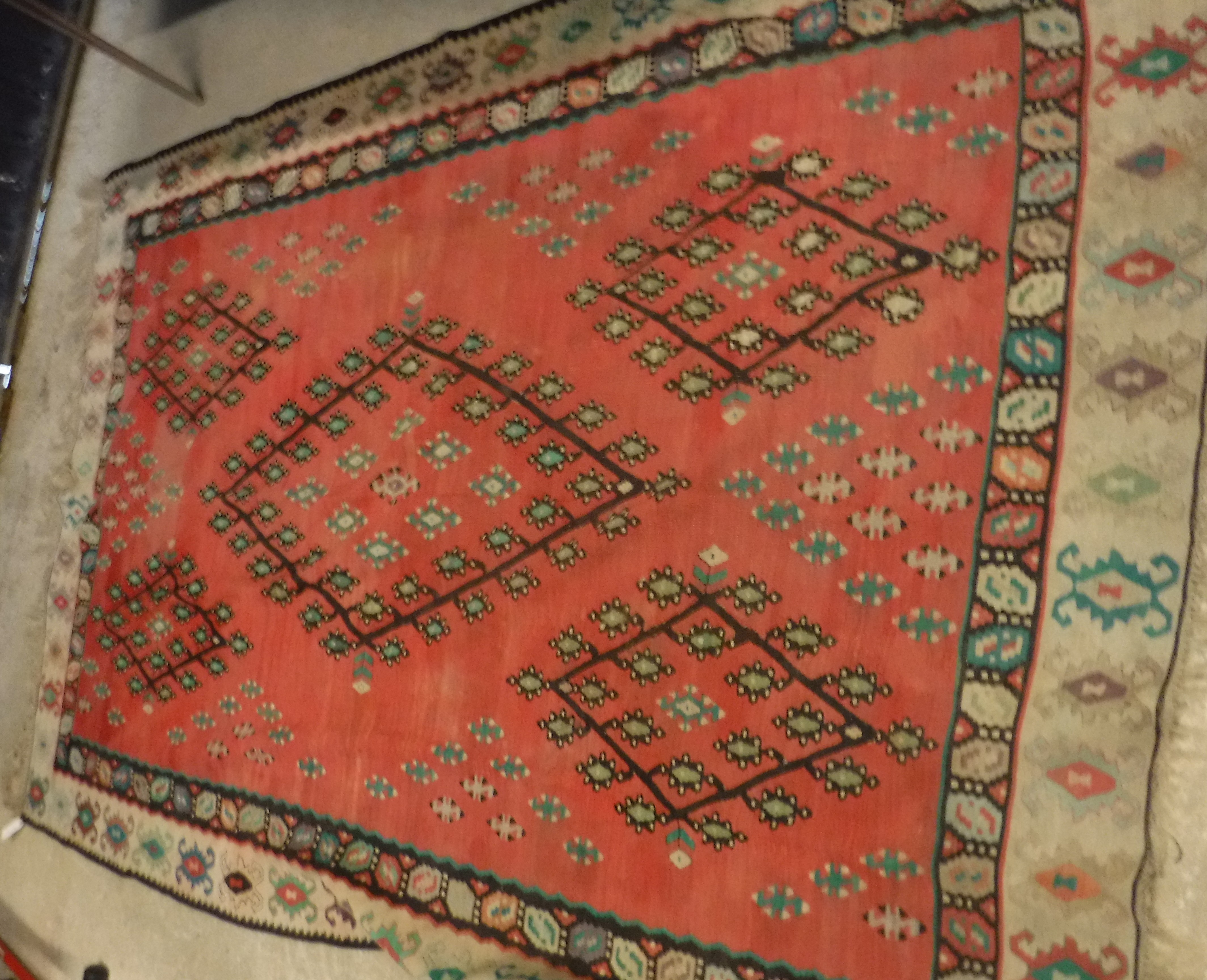A Kelim rug with red ground and green, black and cream decoration,