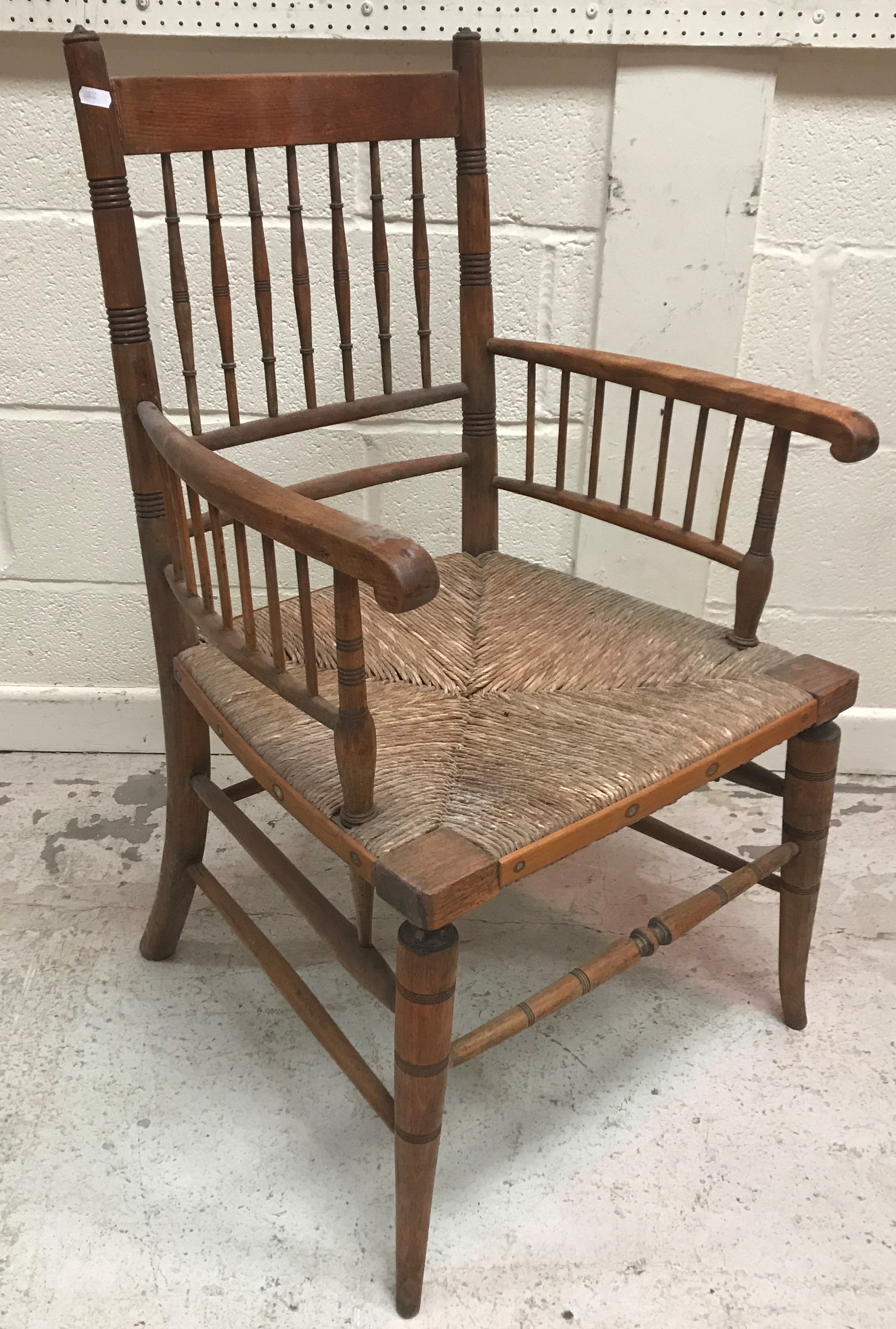 A late 19th Century stained beech framed rush seat spindle back Sussex type armchair after the